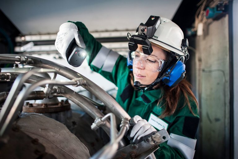 a woman in PPE inspecting equipment on site