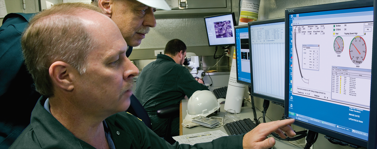 Coiled tubing engineers in the field studying computer screens.