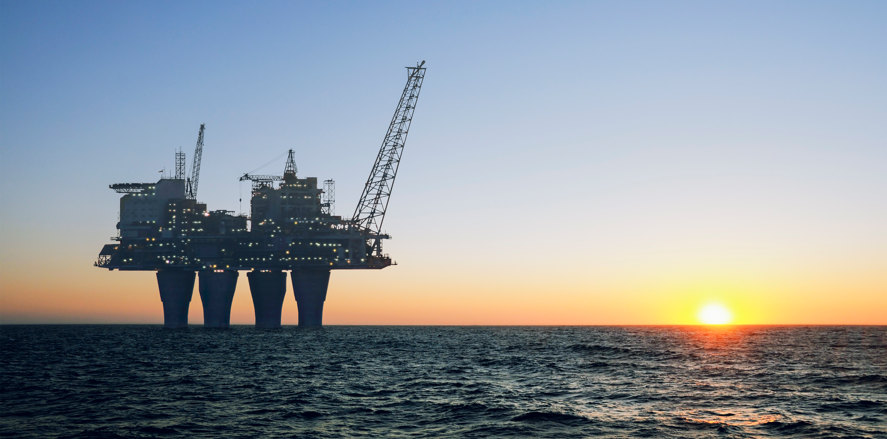 Photo of an offshore oil rig at sunset.