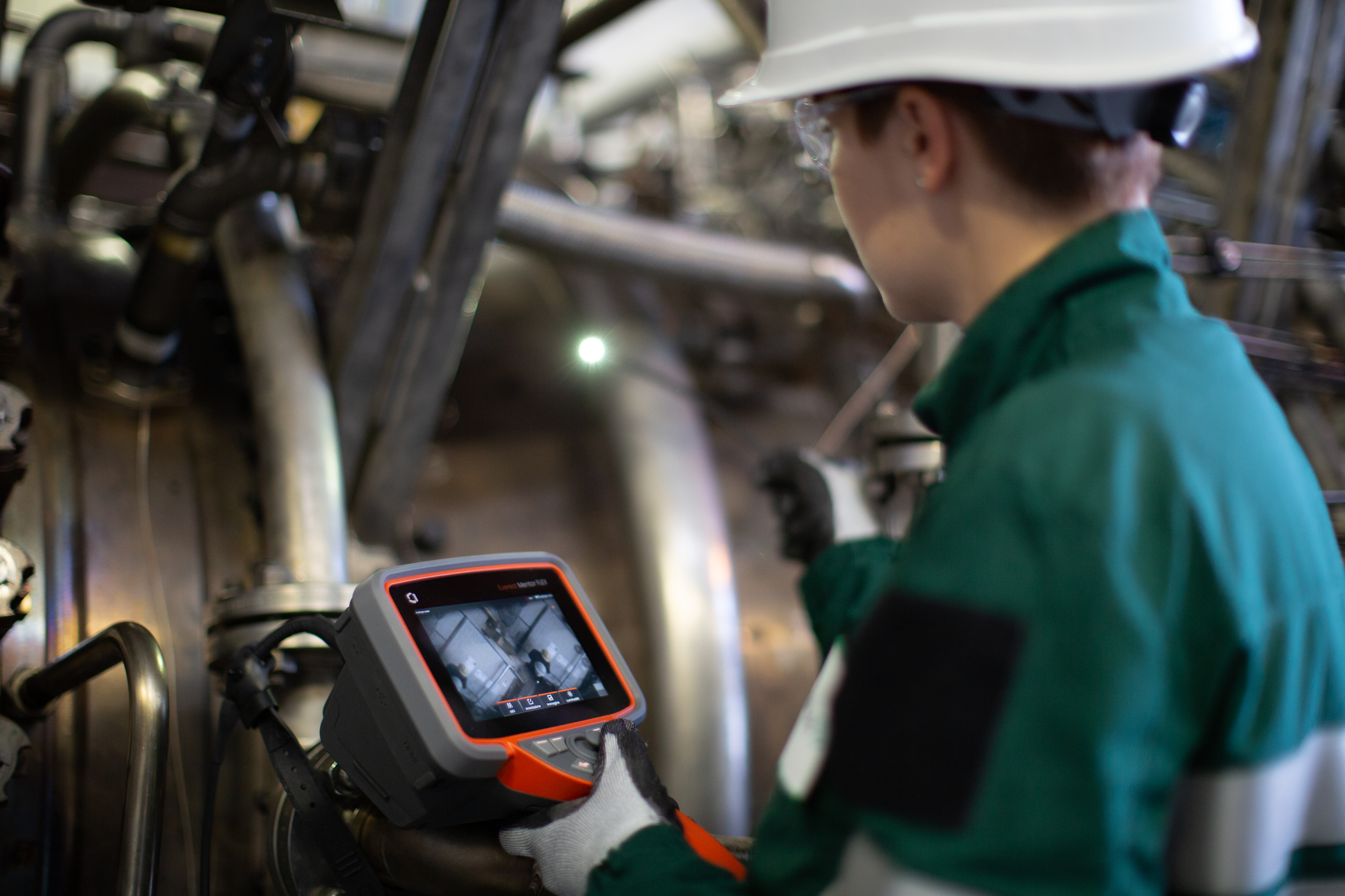 Technician in green suit uses Everest Mentor Flex video borescope to conduct inspection.