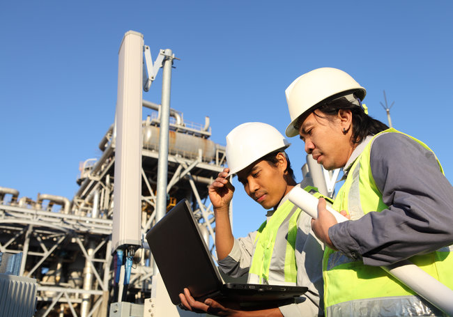Picture of two technicians reviewing inspection template on a laptop in an oil and gas industry.