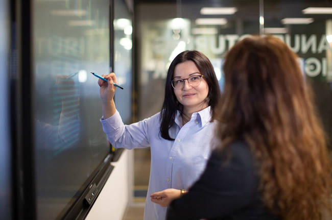 Two people working on a whiteboard.